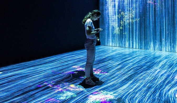 Uma pessoa de pé em uma mostra de arte e tecnologia.