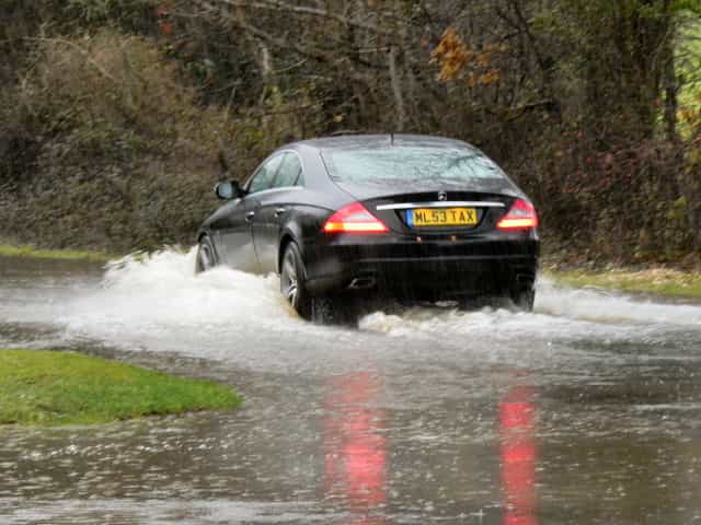 Um carro percorre uma enchente.