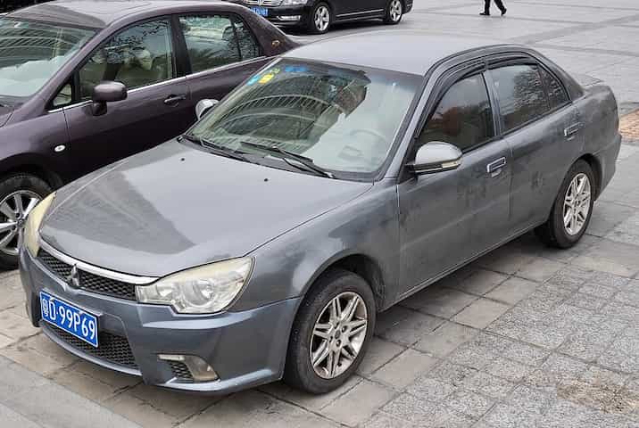 Um sedã cinza da Mitsubishi parado na rua.
