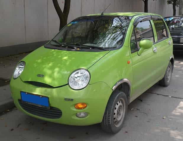 O antigo Chery QQ, de cor verde, parado em uma rua.